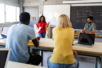 African American teen female high school student giving oral class presentation in front of multiracial classmates.