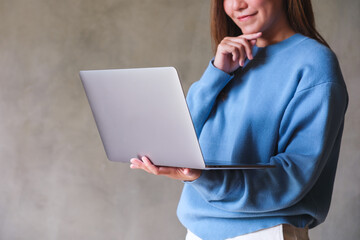 Canvas Print - Closeup image of a young woman holding and working on laptop computer