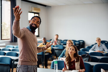 Happy black professor teaching group students during adult education training course in lecture hall.