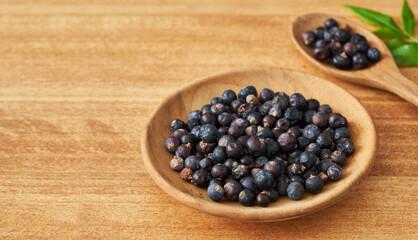 Wall Mural - dry juniper berry seed in wood plate on wooden table background. dry juniper berry seed background. heap of dry juniper berry seed food background                          