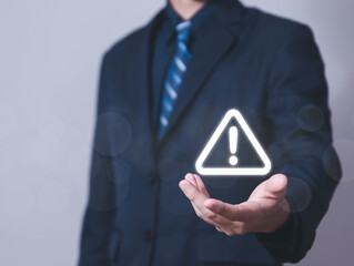 Wall Mural - businessman using laptop showing warning triangle and exclamation sign icon warning of dangerous pro