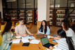 © Drobot Dean - Group of students preparing for exams together while sitting at table in library