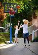 happy kids playing basketball at the driveway of their home. portable basketball hoop stand. active lifestyle. neighborhood activity sports