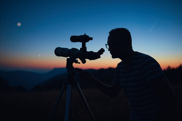 Wall Mural - astronomer looking at the starry skies and crescent moon with a telescope.