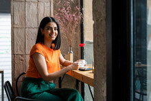 Smiling Young Woman Enjoying Coffee In Cafe