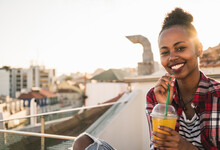 Portrait Of Happy Young Woman Having A Drink On Rooftop At Sunset