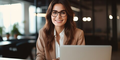 Poster - Happy business woman using laptop, smiling, posing with glasses, working, sitting at workplace in modern office.