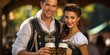 A Bavarian couple in traditional dress holds a mug of beer in their hand.