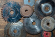 Old circular saw blades and emery wheels on wooden table, closeup, top view. Carpentry tools, sawing and grinding equipment