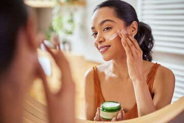 Wall Mural - woman applying face cream during morning routine