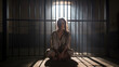 © Sasint - An anxious female prisoner sits on her knees in a cell, beamed with sunlight. through the barred window to her