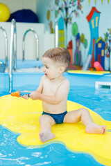 Wall Mural - Development for babies. A little boy is learning to swim in the pool. Children's first swimming lessons. Development for babies