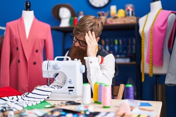 Poster - Young redhead man tailor stressed using sewing machine at clothing factory