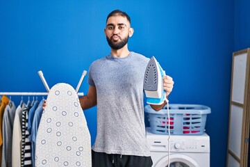 Canvas Print - Middle east man with beard holding electric iron looking at the camera blowing a kiss being lovely and sexy. love expression.