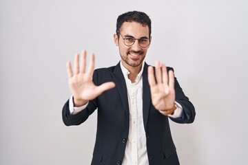 Sticker - Handsome business hispanic man standing over white background showing and pointing up with fingers number nine while smiling confident and happy.