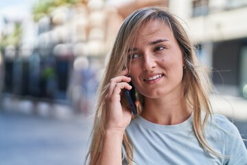 Poster - Young blonde woman smiling confident talking on the smartphone at street