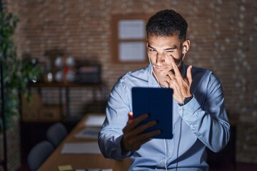 Canvas Print - Handsome hispanic man working at the office at night pointing to the eye watching you gesture, suspicious expression