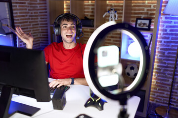 Poster - Young hispanic man playing video games recording with smartphone celebrating achievement with happy smile and winner expression with raised hand