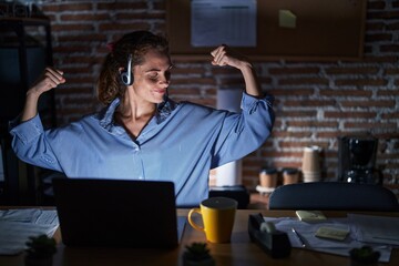 Sticker - Beautiful brunette woman working at the office at night showing arms muscles smiling proud. fitness concept.