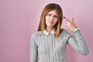 Sticker - Beautiful woman standing over pink background shooting and killing oneself pointing hand and fingers to head like gun, suicide gesture.