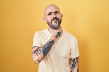 Poster - Hispanic man with tattoos standing over yellow background cutting throat with hand as knife, threaten aggression with furious violence