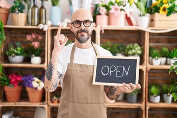 Canvas Print - Hispanic man with tattoos working at florist holding open sign surprised with an idea or question pointing finger with happy face, number one