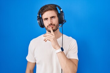 Poster - Hispanic man with beard listening to music wearing headphones thinking concentrated about doubt with finger on chin and looking up wondering