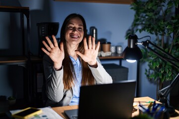 Canvas Print - Young brunette woman working at the office at night showing and pointing up with fingers number ten while smiling confident and happy.