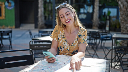 Poster - Young blonde woman tourist using smartphone looking city map at coffee shop terrace