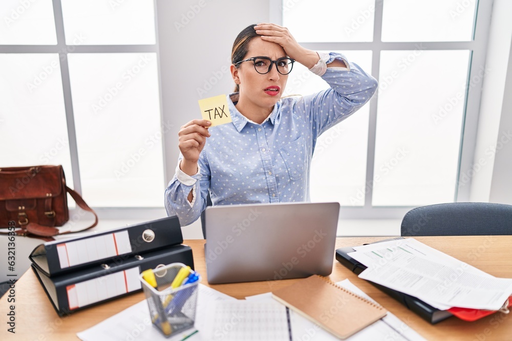 Young hispanic business woman at the office calculating taxes stressed ...