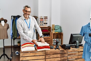 Sticker - Middle age grey-haired man shop assistant folding clothes at clothing store