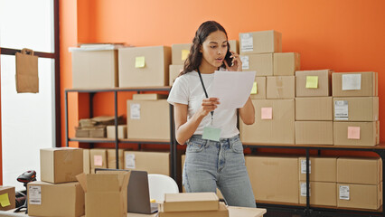 Wall Mural - African american woman ecommerce business worker talking on smartphone reading document at office