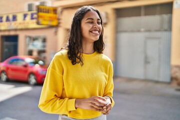 Canvas Print - Young african american woman smiling confident holding earphones at street