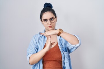 Poster - Young modern girl with blue hair standing over white background doing time out gesture with hands, frustrated and serious face