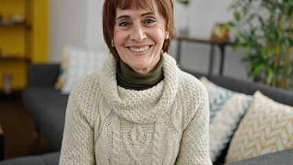 Sticker - Mature hispanic woman smiling confident sitting on sofa at home