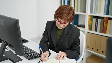 Sticker - Mature hispanic woman teacher using computer taking notes at library university