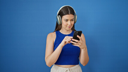 Poster - Young beautiful hispanic woman listening to music standing over isolated blue background