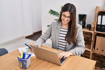 Canvas Print - Young beautiful hispanic woman business worker using smartphone and laptop at office