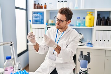 Sticker - Young hispanic man scientist holding test tubes at laboratory