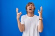 © Krakenimages.com - Middle age man standing over blue background crazy and mad shouting and yelling with aggressive expression and arms raised. frustration concept.