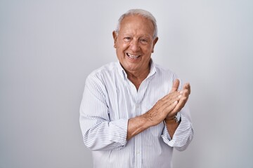 Sticker - Senior man with grey hair standing over isolated background clapping and applauding happy and joyful, smiling proud hands together