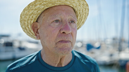 Poster - Senior grey-haired man tourist wearing summer hat with relaxed expression at port