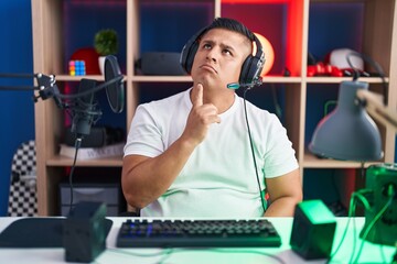 Sticker - Young hispanic man playing video games thinking concentrated about doubt with finger on chin and looking up wondering