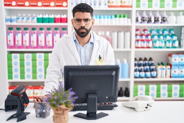 Poster - Hispanic man with beard working at pharmacy drugstore skeptic and nervous, frowning upset because of problem. negative person.