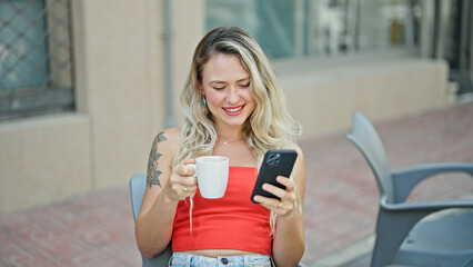 Sticker - Young blonde woman using smartphone drinking coffee at coffee shop terrace