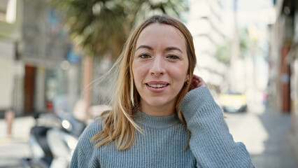 Wall Mural - Young blonde woman smiling confident standing at street