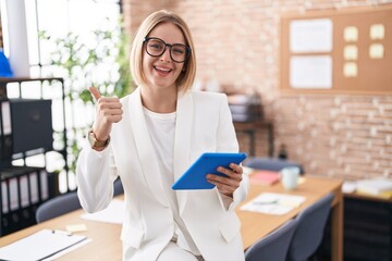 Sticker - Young caucasian woman working at the office wearing glasses doing happy thumbs up gesture with hand. approving expression looking at the camera showing success.