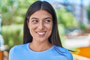 Wall Mural - Young beautiful hispanic woman smiling confident looking to the side at park