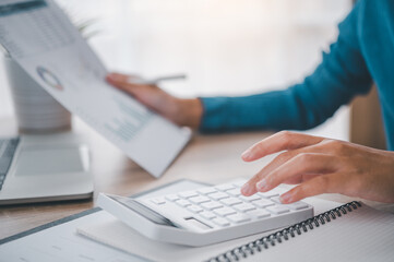 close up The business person is sitting on a calculator with a graph in the office of finance accounting concept