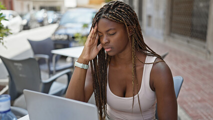 Canvas Print - African american woman using laptop sitting on table tired at coffee shop terrace